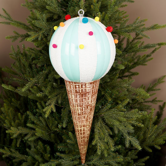 Decorative ice cream cone ornament with colorful sprinkles on a Christmas tree.
