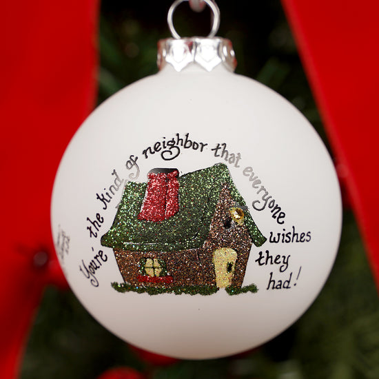 Decorative Christmas ornament with a house illustration and text on a white background.