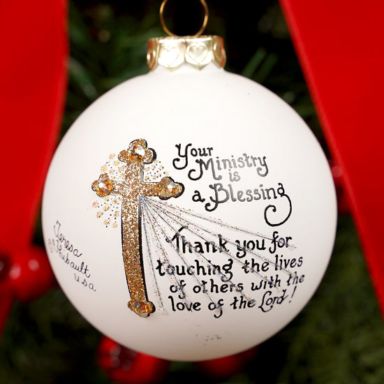 Decorative Christmas ornament with a cross and text on a white background.