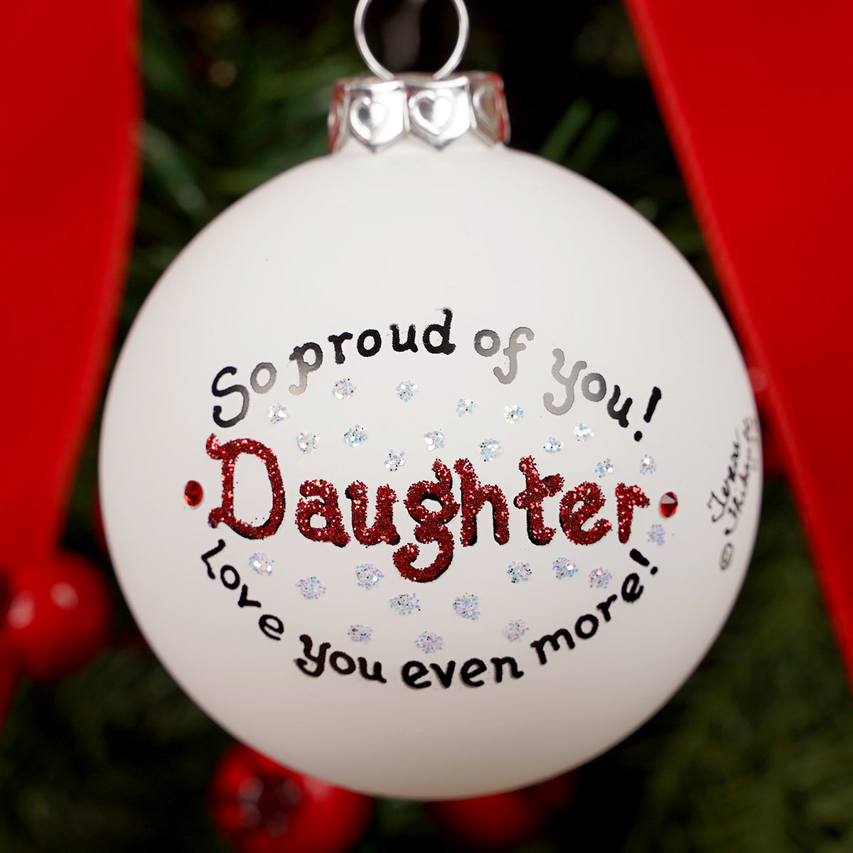 Christmas ornament with text 'So proud of you! Daughter, love you even more!' on a tree.
