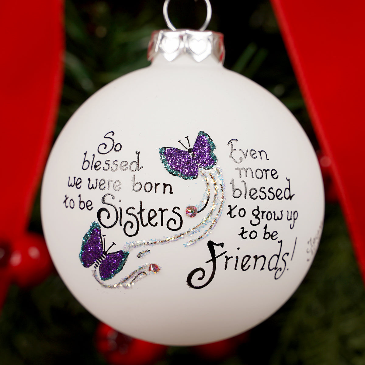 Decorative ornament with butterfly design and text about sisters and friends on a blurred background.