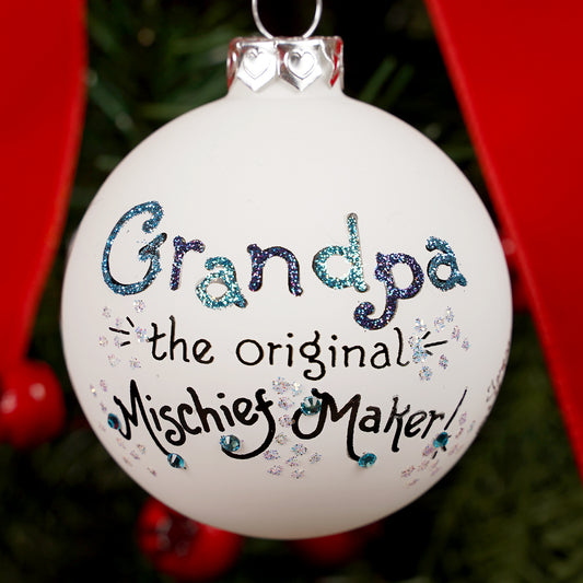 Decorative Christmas ornament with 'Grandpa the original Mischief Maker' text on a tree.