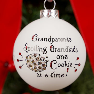Decorative Christmas ornament with text 'Grandparents Spoiling Grandkids one Cookie at a time' on a blurred background.