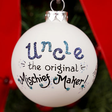White ornament with text 'Uncle the original Mischief Maker' on a Christmas tree.
