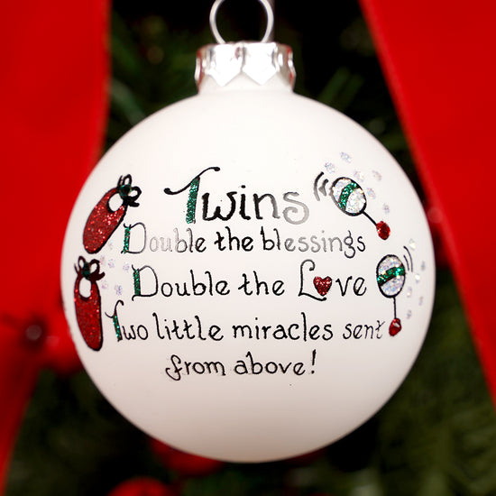Decorative Christmas ornament with text about twins on a tree.