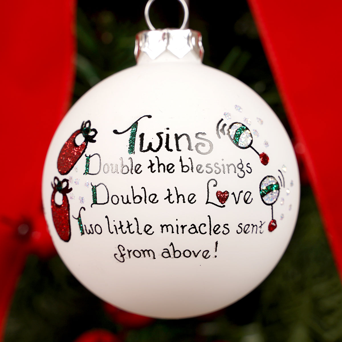 Decorative Christmas ornament with text about twins on a tree.