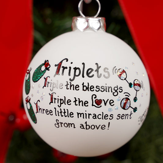 Decorative ornament with text about triplets on a Christmas tree.