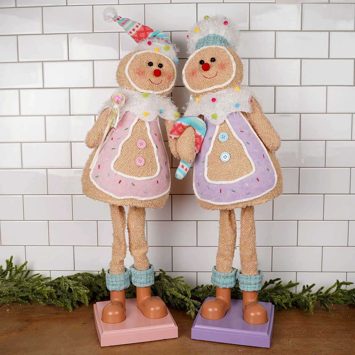 Two decorative gingerbread figures with colorful outfits against a white tiled wall.