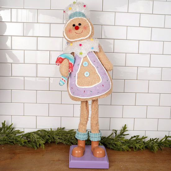 Decorative gingerbread man figure with a colorful outfit against a white tiled wall.