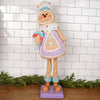 Decorative gingerbread man figure with a colorful outfit against a white tiled wall.