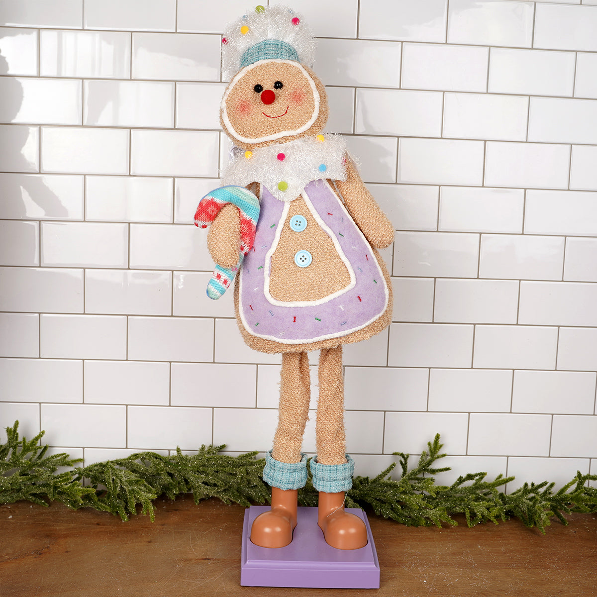 Decorative gingerbread man figure with a colorful outfit against a white tiled wall.