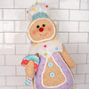 Toy gingerbread man with colorful buttons and scarf against a tiled wall background