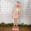 Christmas Place Decorative gingerbread man figurine with a pink apron against a white tiled wall.