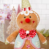 Gingerbread man plush toy with a polka dot hat and bow tie in a festive setting.