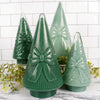 Set of green ceramic Christmas trees with bow details on a marble surface.