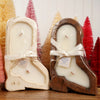 Two candles in wooden boot molds with decorative trees in the background