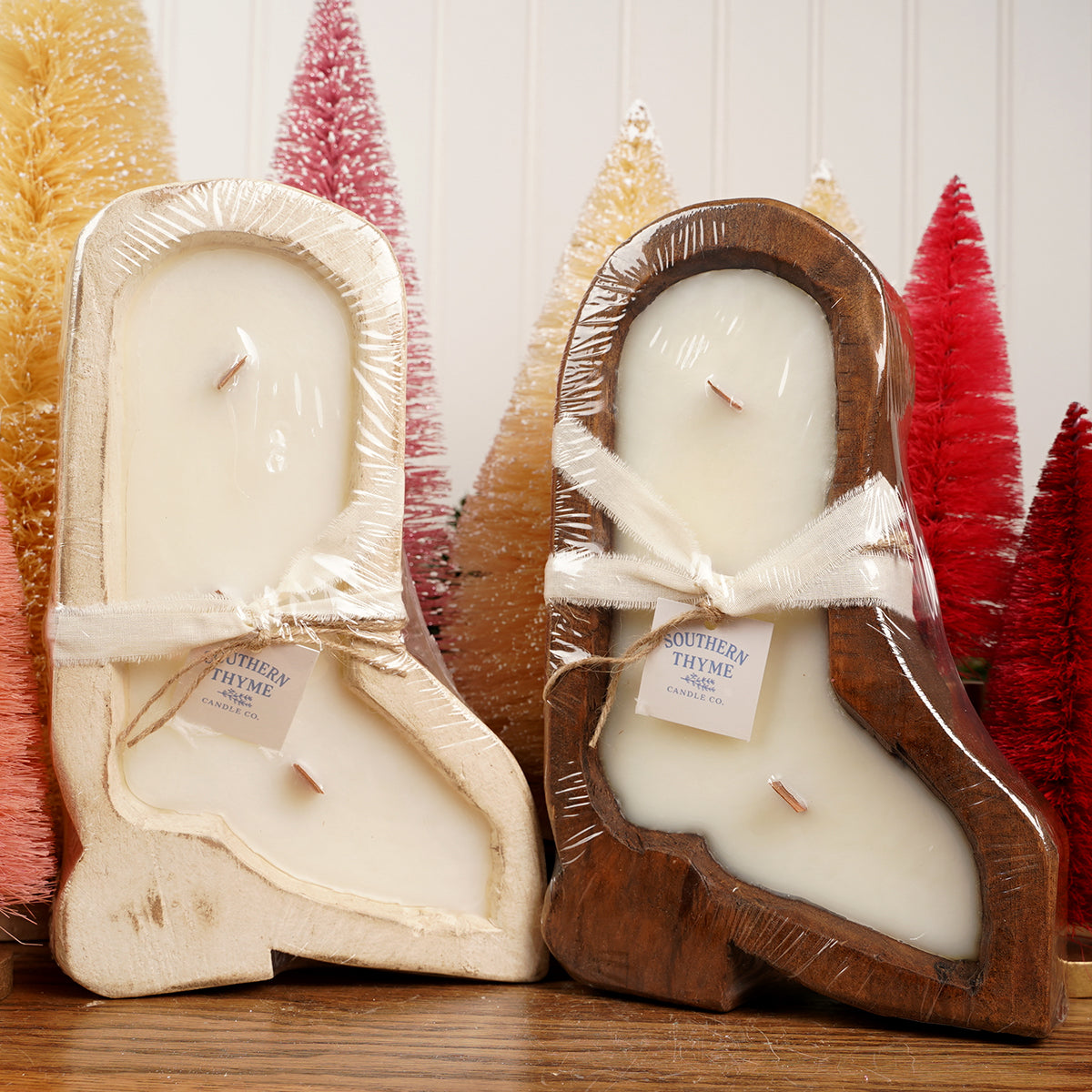 Two candles in wooden boot molds with decorative trees in the background