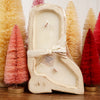 Decorative candle in a decorative boot holder with Christmas trees in the background
