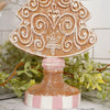 Decorative Christmas tree ornament with gold glitter and white patterns on a marble surface with greenery.